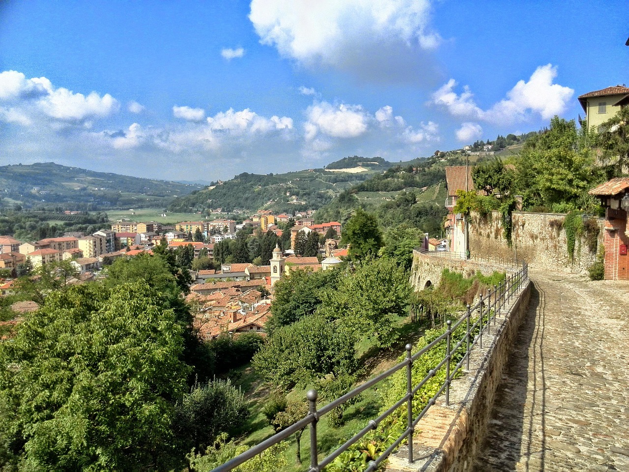 Colline verdi del Monferrato con vigneti e cieli blu, simbolo di bellezza naturale e cultura enogastronomica.