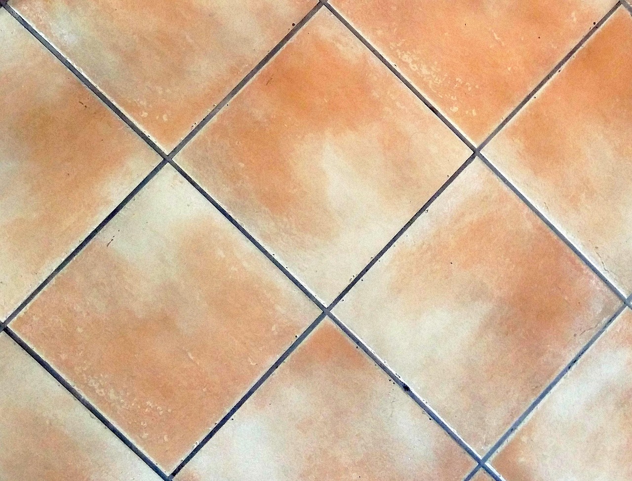 Immagine di fughe sporche tra piastrelle con prodotti per la pulizia e attrezzi.