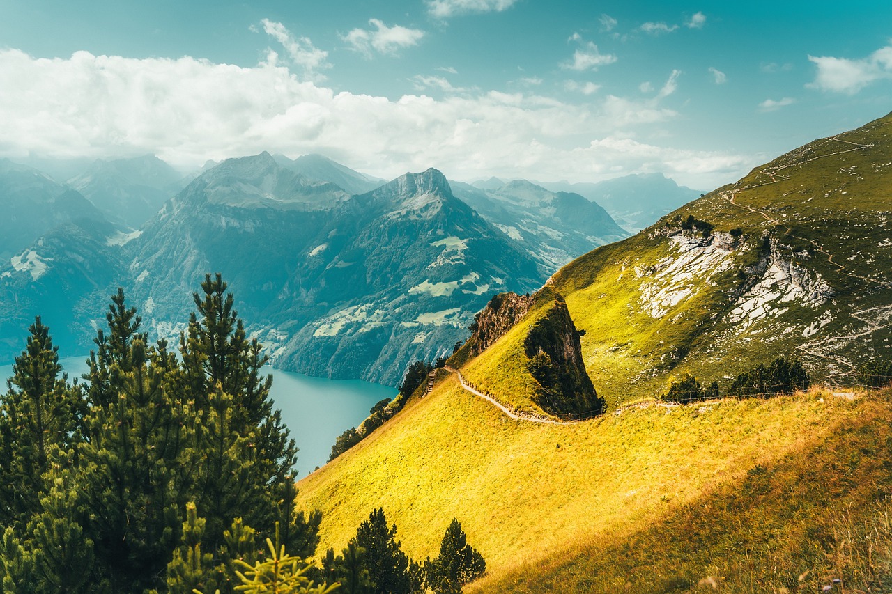 Panorama alpino estivo con montagne verdi e cielo blu, ideale per vacanze fuori stagione.